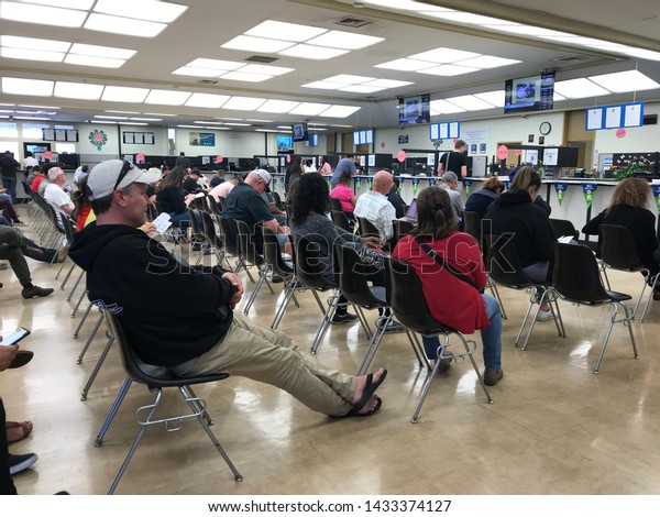 LOS ANGELES, April 25,\
2019: DMV Department of Motor Vehicles Culver City. Long rows of\
chairs with people sitting, waiting their turn, inside the busy\
waiting room area.