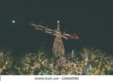 Los Angeles, CA, December 2018: Annual Holiday Lights At The Grove. Santa Sleighing With Reindeer In Front Of A Christmas Tree In A Cold, Dark Night