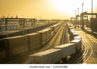 Los Angeles, CA - June 29, 2018: Western view of sunset over the cargo train cars and freight cranes at an industrial train station.