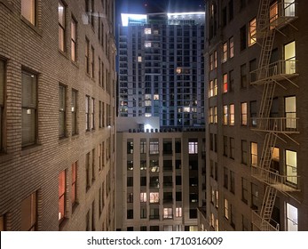 LOS ANGELES, CA, MAR 2020: Apartment Windows At Night In Downtown Buildings, Looking From 1920s Building With External Fire Escape Towards Modern Condos