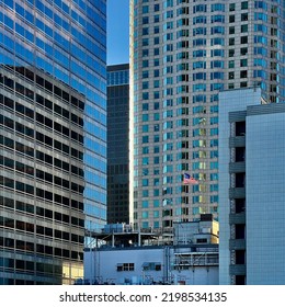 LOS ANGELES, CA, MAR 2022: Shaft Of Sunlight Lights Up The Stars And Stripes, US Flag Flying Between Skyscrapers In Downtown Financial District