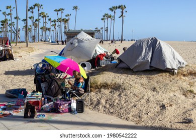 Los Angeles, CA | United States - May 22, 2021: Homeless people with tents set up behind vendors on the Venice Beach boardwalk