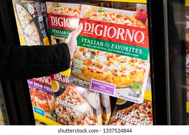 Los Angeles, CA, USA 03/12/2019 - Shopper Holding A Box Of Di Giorno Brand Frozen Pizza At A Supermarket Freezer