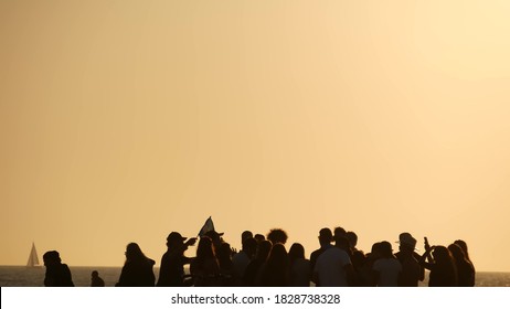 LOS ANGELES CA USA - 16 NOV 2019: California, Happy Young Multiracial Friends Having Fun And Hanging Out. Group Of Multiethnic People Dancing On Party In Sunset Light. Venice Beach Summertime Leisure.