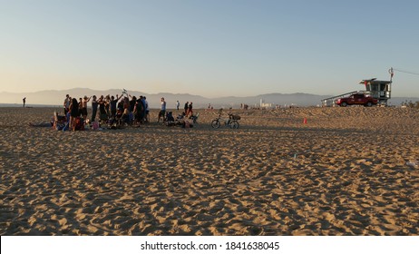 LOS ANGELES CA USA - 16 NOV 2019: California, Happy Young Multiracial Friends Having Fun And Hanging Out. Group Of Multiethnic People Dancing On Party In Sunset Light. Venice Beach Summertime Leisure.