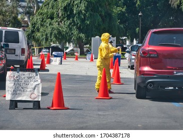 Los Angeles, CA / USA - 4/14/20: A Health Care Worker In A Hazmat Suit Directs People In Their Cars During The COVID Outbreak. 