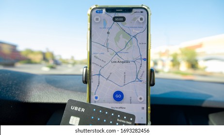 Los Angeles, CA, USA 4/4/2020 — Uber Rideshare Driver Holding A Uber Business Debit Card In Front Of The IPhone 11 With The Driver App Open. Downtown Los Angeles Shown On Map.