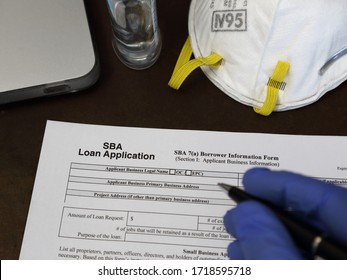 Los Angeles, CA / USA - Apr 30, 2020: A Rubber Gloved Hand Is Shown About To Fill Out A Small Business Administration Aka SBA Loan Application Form, With An N95 Respirator Dust Mask Nearby.