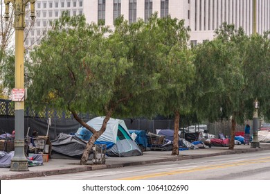 Los Angeles, CA, USA - April 5, 2018: Row of tents and sleeping bags on sidewalk of N. Grand Street downtown. Back is High rise office building. People, shopping carts and garbage.