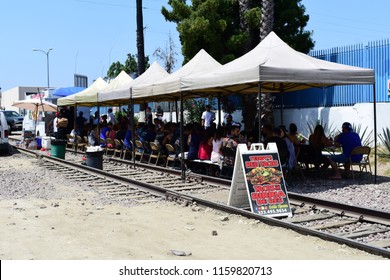 Los Angeles, CA / USA - August 19 2018: A Mexican Taco Food Truck With Tables All Stationed On Top Of The Railroad Tracks In South Central LA