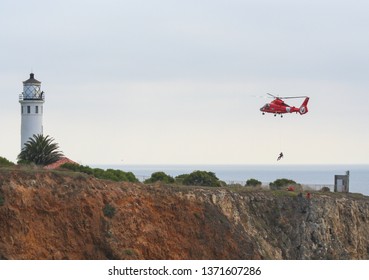 Los Angeles, CA / USA - February 14, 2006: A Bright Red US Coast Guard Dolphin Helicopter Conducts Training Rescue Operations Off Point Vicente California, Rescuing A Man Off The Cliff.