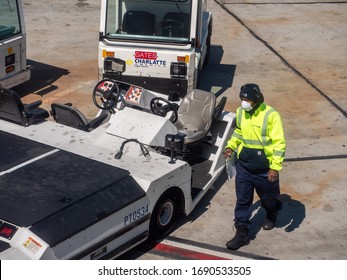 Los Angeles, CA / USA - March 27 2020: United Airlines Ramp Worker, Critical Infrastructure Essential Employee, Wears A Mask To Prevent Spread Of COVID-19. Walking With Clipboard To Pushback Tug