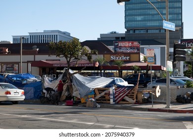 Los Angeles, CA USA - Novmber 14, 2021:  Homeless encampment in front of a Sizzler restaurant with a banner promoting Thanksgiving dinner 
