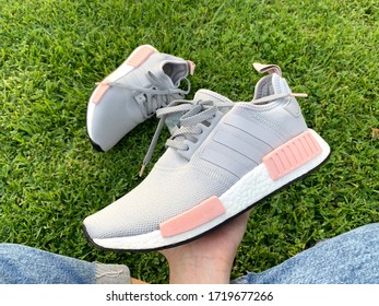 LOS ANGELES, CALIFORNIA - APRIL 14, 2017: CLOSE UP ADIDAS NMD IN GREY AND PINK WOMEN SHOES ON HAND WITH LEGS. TOP VIEW.