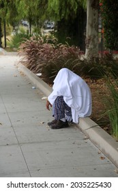 Los Angeles, California. August 17, 2021: Los Angles Homeless person talks to himself as he sits on a sidewalk covered with a sheet. The Homeless crisis is very terrible in Los Angeles California.