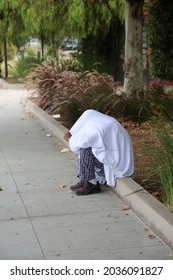 Los Angeles, California. August 17, 2021: Los Angles Homeless person talks to himself as he sits on a sidewalk covered with a sheet. The Homeless crisis is very terrible in Los Angeles California.