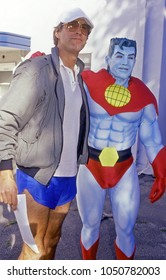 Los Angeles, California - Exact Date Unknown - Circa 1990: Comedian And Actor Chevy Chase Posing With Captain Planet At A Celebrity Event