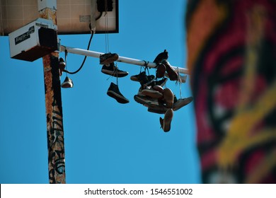 Los Angeles, California / united states - October 23 2019: Several pairs of shoes  hanging on an electrical line as a symbol of a meeting place for drug dealers graffiti painted pole in bokeh faded