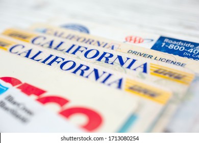 Los Angeles, California, United States - 02-06-2020: A closeup view of several California driver licenses among other wallet cards on a wooden surface.