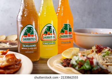 Los Angeles, California, United States - 10-02-2021: A view of several bottles of Jarritos soda next to Mexican food entrees.