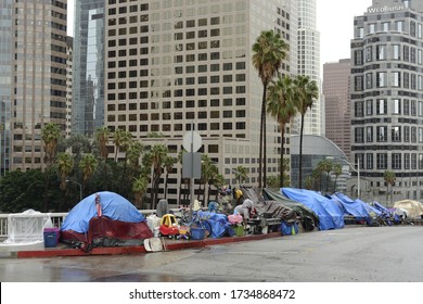 Los Angeles, California, USA - December 6, 2018: Homeless tents lining offramp to freeway, downtown Los Angeles. Children's toys in front of one tent. High rise buildings in background.