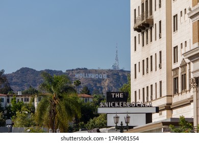 LOS ANGELES, CALIFORNIA, USA - JUNE 26, 2013: Famous Landmark Hollywood Sign At The Top Of The Mount Lee Seen Behind The Palm Trees, Some Houses And The Old Historical Hotel Theater The Knickerbocker.