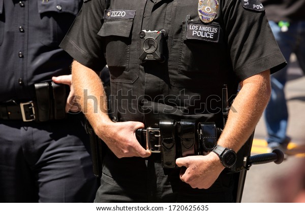Los Angeles, California / USA - May 1, 2020: A Los\
Angeles Police (LAPD) Officer wearing a body camera stands watch\
outside of City Hall. 