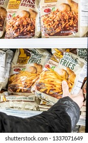 Los Angeles, CA/USA 3/12/2019 Human Hand Holding A Package Of Idaho Grown Brand Frozen French Fries In A Supermarket Freezer