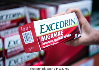 Los Angeles, CA/USA 7-1-2019 Shoppers Hand Holding A Box Of Excedrin Brand Genuine Migraine Acetaminophen Tablets In Supermarket Aisle