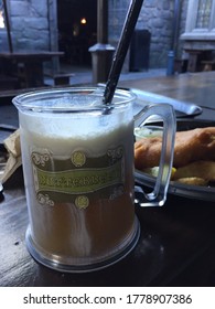 Los Angeles, CA/USA - December, 2018: Butterbeer in a mug on a wooden table with a castle wall on background at Three Broomsticks, the Wizarding World of Harry Potter at Universal Studios, no people