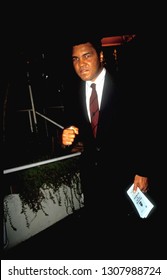 Los Angeles - Circa 1991: Muhammad Ali Mugs For Photographers Leaving Spago Restaurant. He Holds A Brochure 