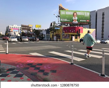 LOS ANGELES, Dec 12,2018: A Pedestrian Crosses The Street At A Red Painted Curb Extension On Sunset Boulevard In West Hollywood,part Of The Sunset Experience Pilot Project To Improve Pedestrian Safety