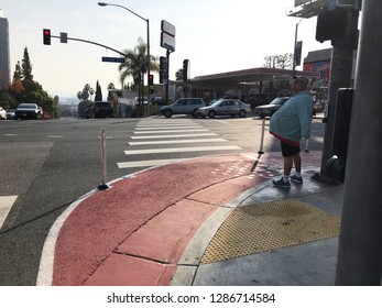 LOS ANGELES, Dec 12th, 2018: A Pedestrian Waits At A Red Painted Curb Extension On Sunset Boulevard In West Hollywood, Part Of The Sunset Experience, A Pilot Project To Improve Pedestrian Safety.