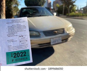 LOS ANGELES, DEC 26th, 2020: DMV California registration tags 2022, attached to renewal notice, close up next to front of golden Toyota car and license plate in a residential neighborhood.