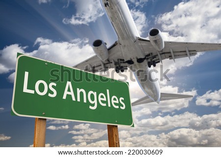 Los Angeles Green Road Sign and Airplane Above with Dramatic Blue Sky and Clouds.