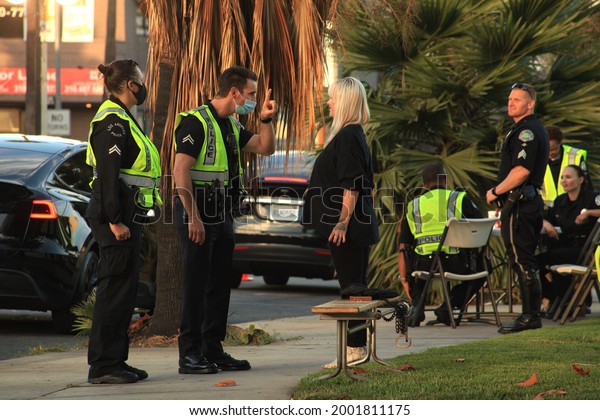 Los\
Angeles - July 2, 2021:\
Los Angeles Police officers perform a\
field sobriety test on blonde female day\
exterior