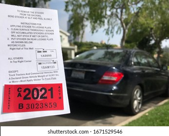 LOS ANGELES, March 5th, 2020: Department of Motor Vehicles DMV California registration tag sticker attached to renewal notice close up, next to the back of a parked black Mercedes luxury car.
