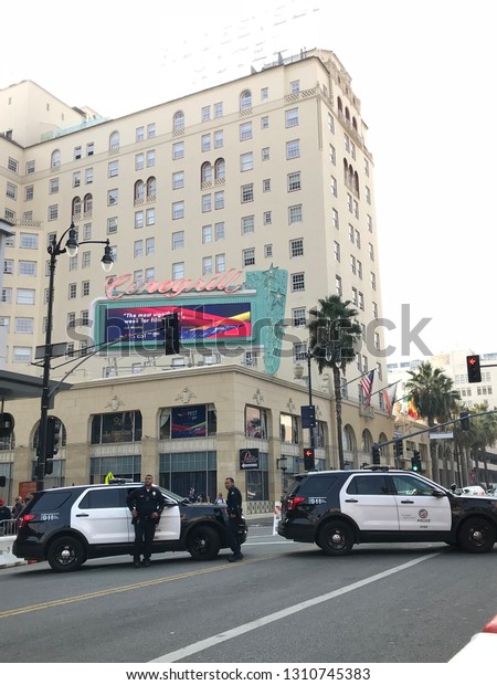 LOS ANGELES, Nov 10th,\
2018: Two police officers stand in front of two police cruisers\
parked across closed off Hollywood Boulevard, in front of the\
Roosevelt hotel.