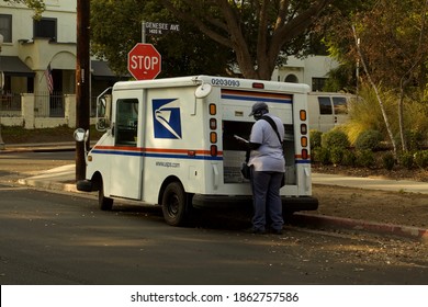 Los Angeles - November 23, 2020: U.S. Postal Service Mail Carrier At Rear Of Van