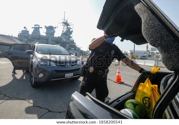 A Los Angeles Port Police officer loads food into the
trunk of a vehicle during a Thanksgiving Turkey Giveaway at the
Battleship USS Iowa Museum parking lot in Los Angeles Friday, Nov.
20, 2020. 