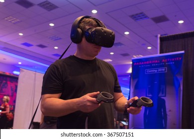 Los Angeles, USA - January 23, 2016: Man tries virtual reality HTC Vive headset and hand controls during VRLA Expo Winter, virtual reality exposition, at the Los Angeles Convention Center.