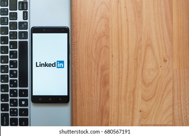 Los Angeles, USA, july 18, 2017: Linkedin on smartphone screen placed on the laptop on wooden background.