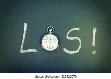 LOS (deutsches Wort für "Go") handgeschriebenes Wort auf der Tafel mit einer präzisen Stoppuhr, die anstelle von O verwendet wird 