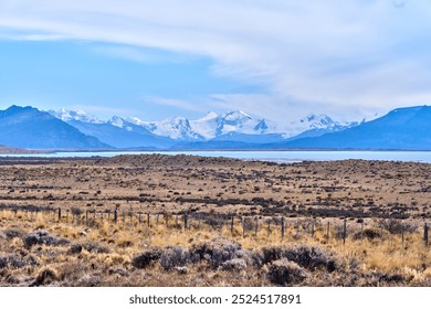 Los Glaciares National Park, Perito Moreno, Patagonia, showcasing a vast landscape of snow-capped mountains, tranquil lakes, and arid grasslands under a clear blue sky. - Powered by Shutterstock