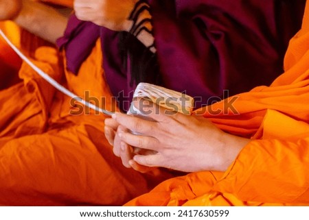 
lose up monk's hand holding holy thread, buddhist holy day, thai buddhist monk ordination ceremony wallpaper background concept