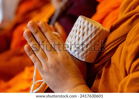 
lose up monk's hand holding holy thread, buddhist holy day, thai buddhist monk ordination ceremony wallpaper background concept
