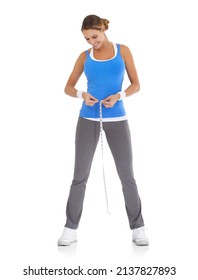 Losing inches and feeling great. Young woman in sportswear measuring her waistline while isolated on white.