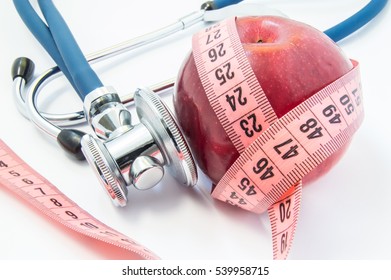 
Losing Weight With Healthy Food (fruits And Vegetables) Under Doctor Supervision. Red Apple Wrapped Up By Measuring Tape And Stethoscope, Which Exam Of Apple. Concept For Healthy Eating, Weight Loss