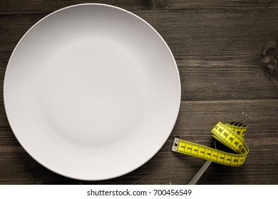 Losing Weight. Strict Diet. Empty Plate And Measuring Tape On Fork Instead Food On Wooden Background Top View Mockup