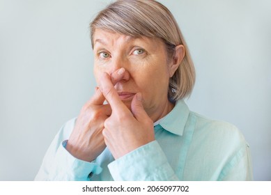 Loss Of Smell. Senior Woman Touches Her Nose With Her Fingers Because Of The Loss Of Her Sense Of Smell. Self-diagnosis Covid-19. Symptoms Of Coronavirus.